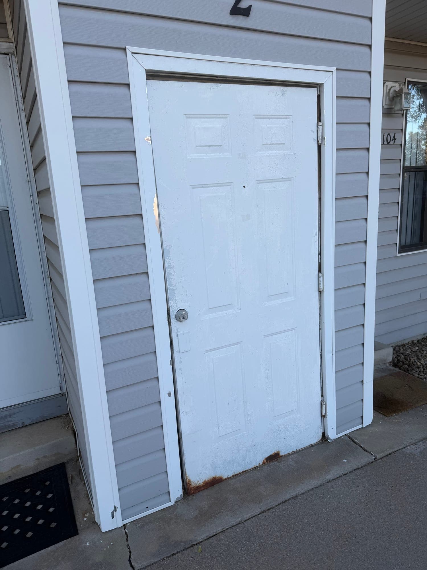 Damaged utility door and trim — IMG_1045: June 2026 condition photo showing a white utility/closet door with worn paint, dark staining, and weathered trim.