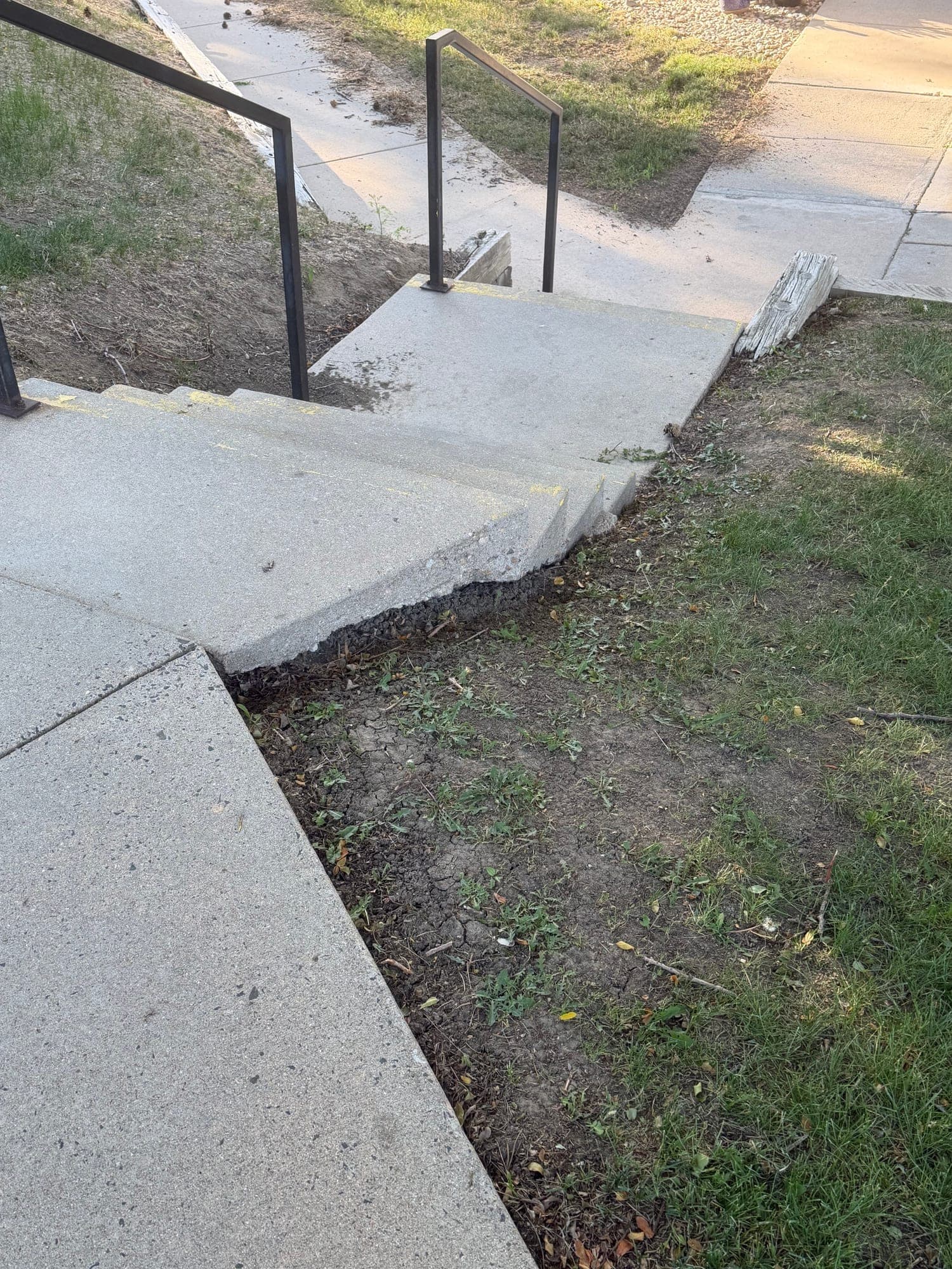 Sunken walkway and eroded grade — IMG_1047: June 2026 condition photo showing a common walkway with a sunken/uneven transition and eroded surrounding grade.