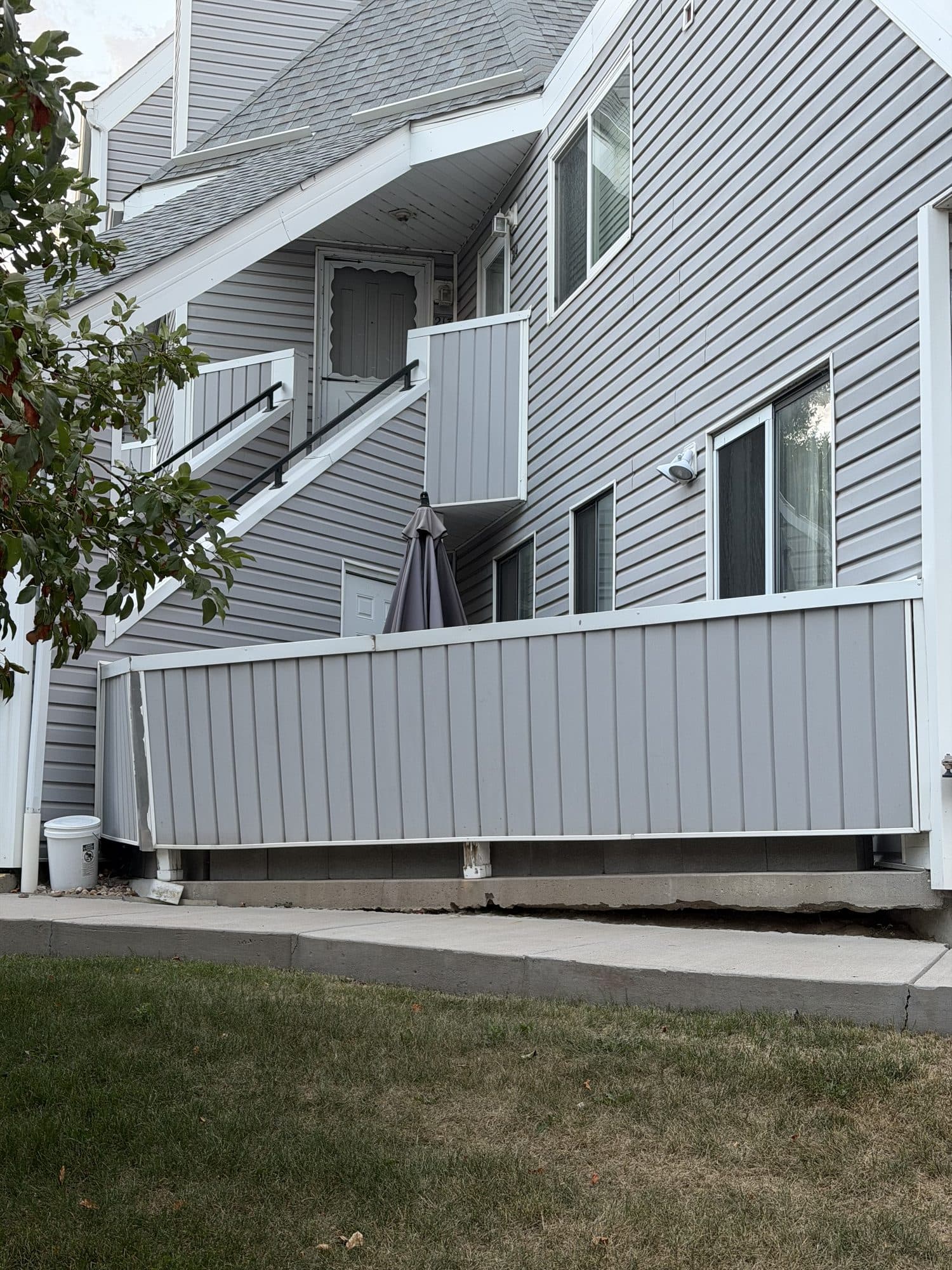 Building exterior and perimeter fence — IMG_1056: Gray-sided building elevation with white perimeter fencing and lawn.