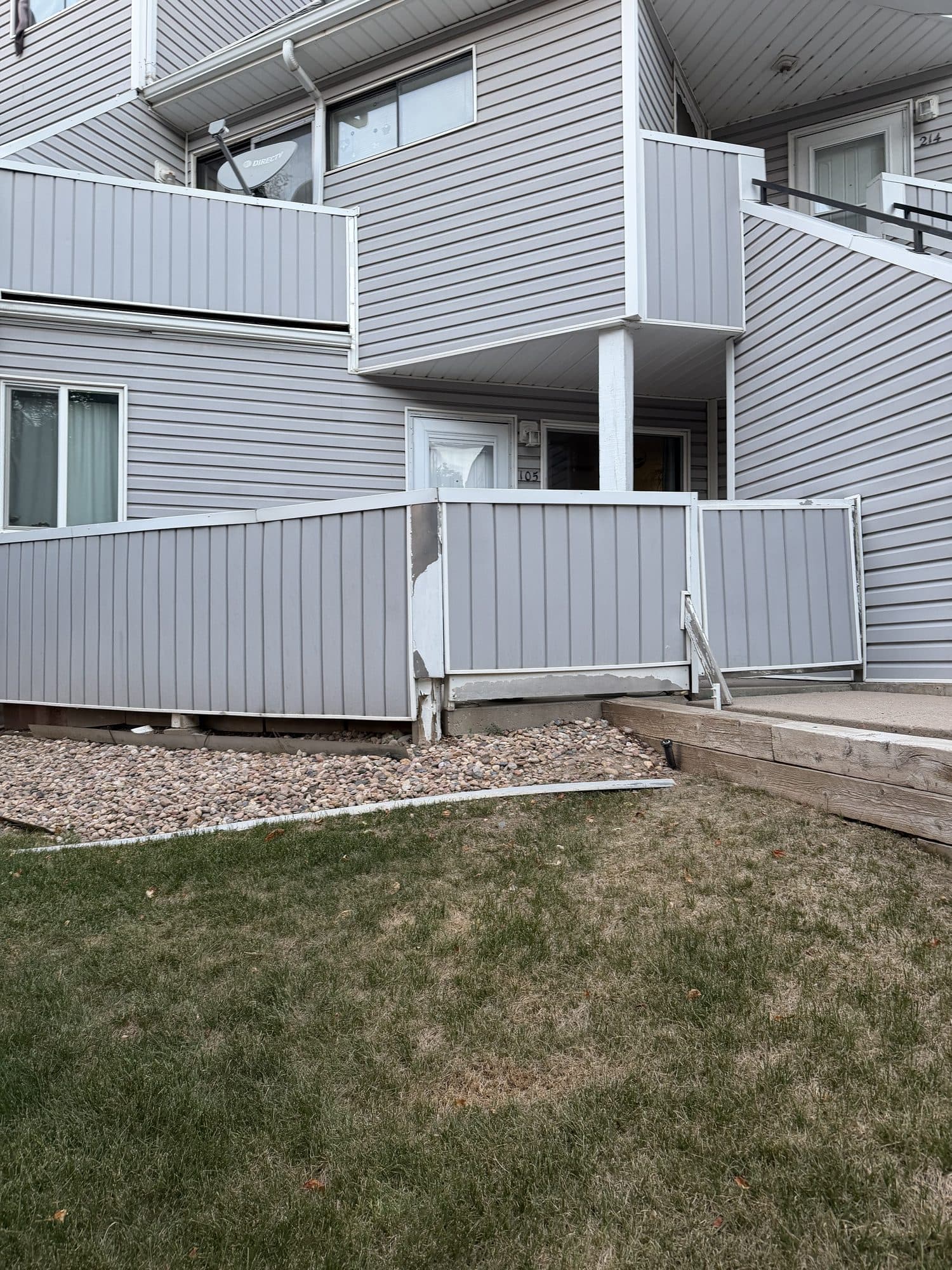 Two-story elevation and walkway — IMG_1057: Building elevation with balconies, perimeter fence, and an entry walkway.
