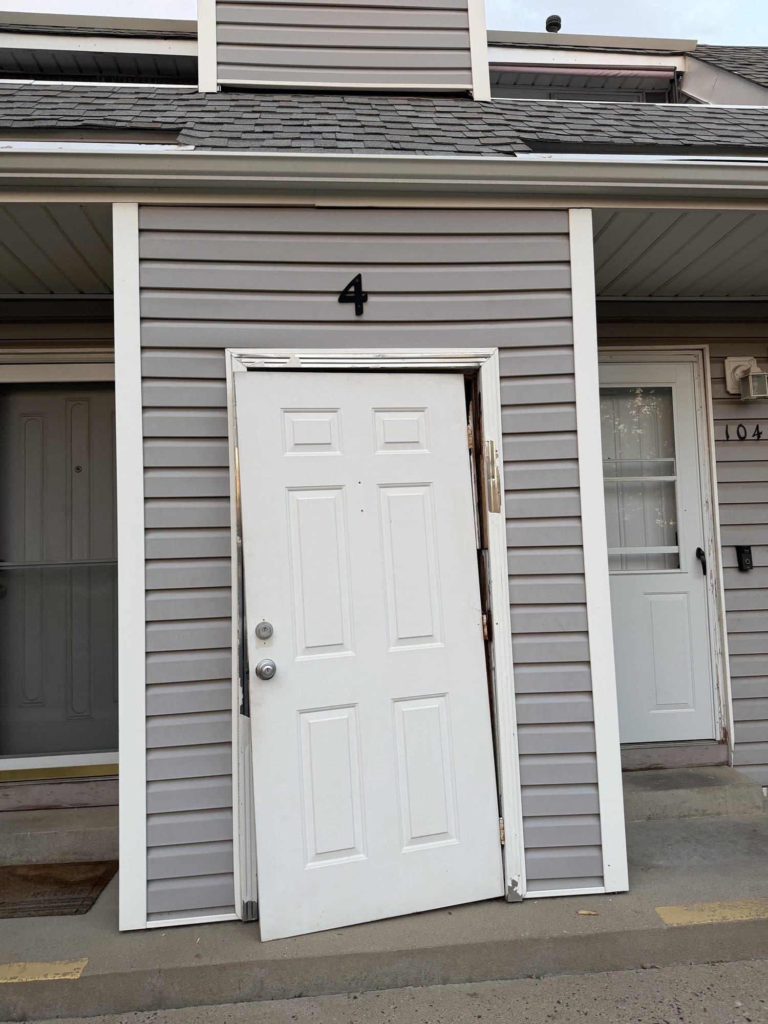 Unit 4 entry door off its hinges — IMG_1062: A six-panel entry door at unit 4 detached from its hinges and sagging out of the frame — a security and safety hazard.