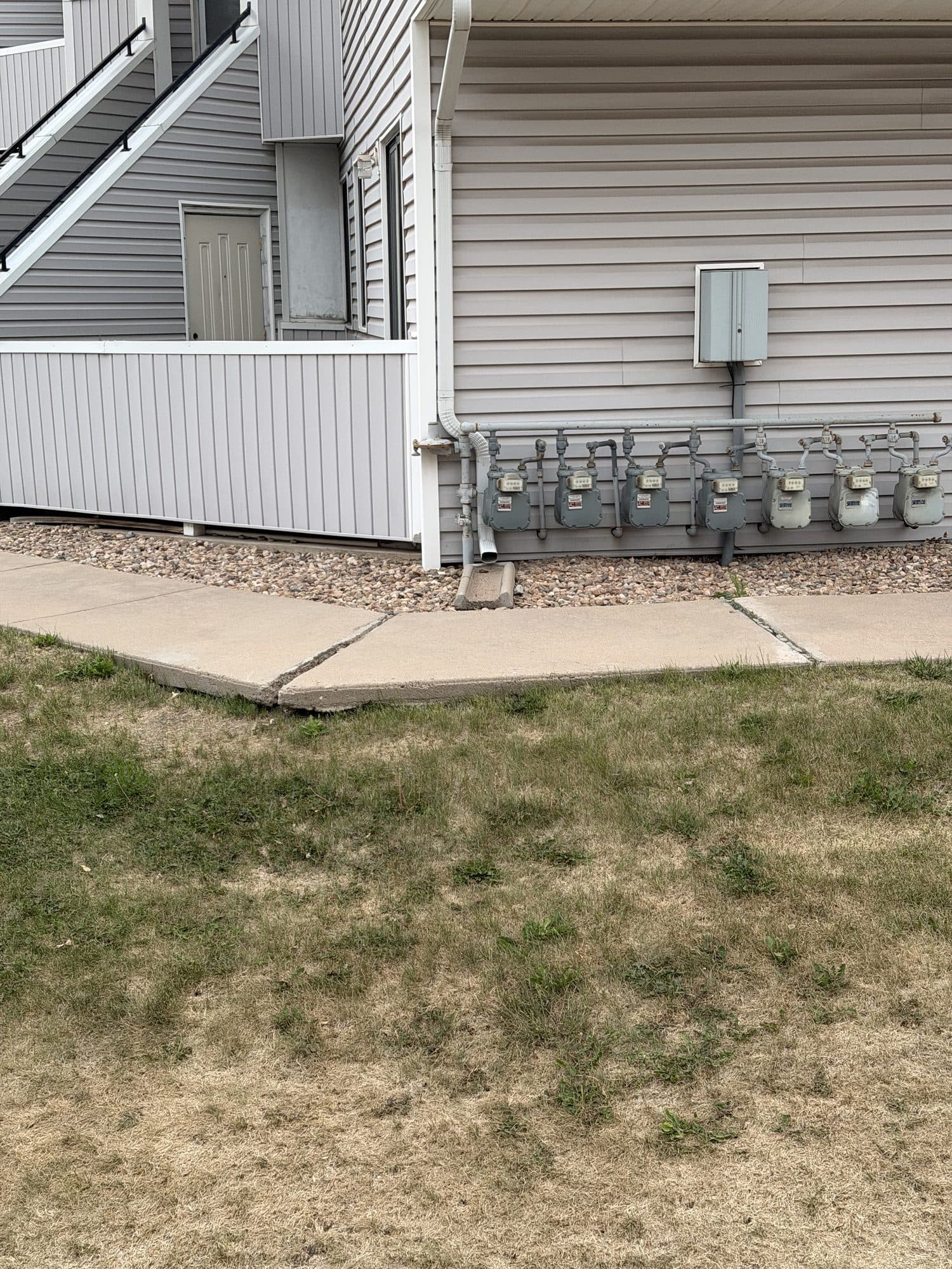 Building base and utility meters — IMG_1069: Base of building siding with adjacent utility meters at grade.