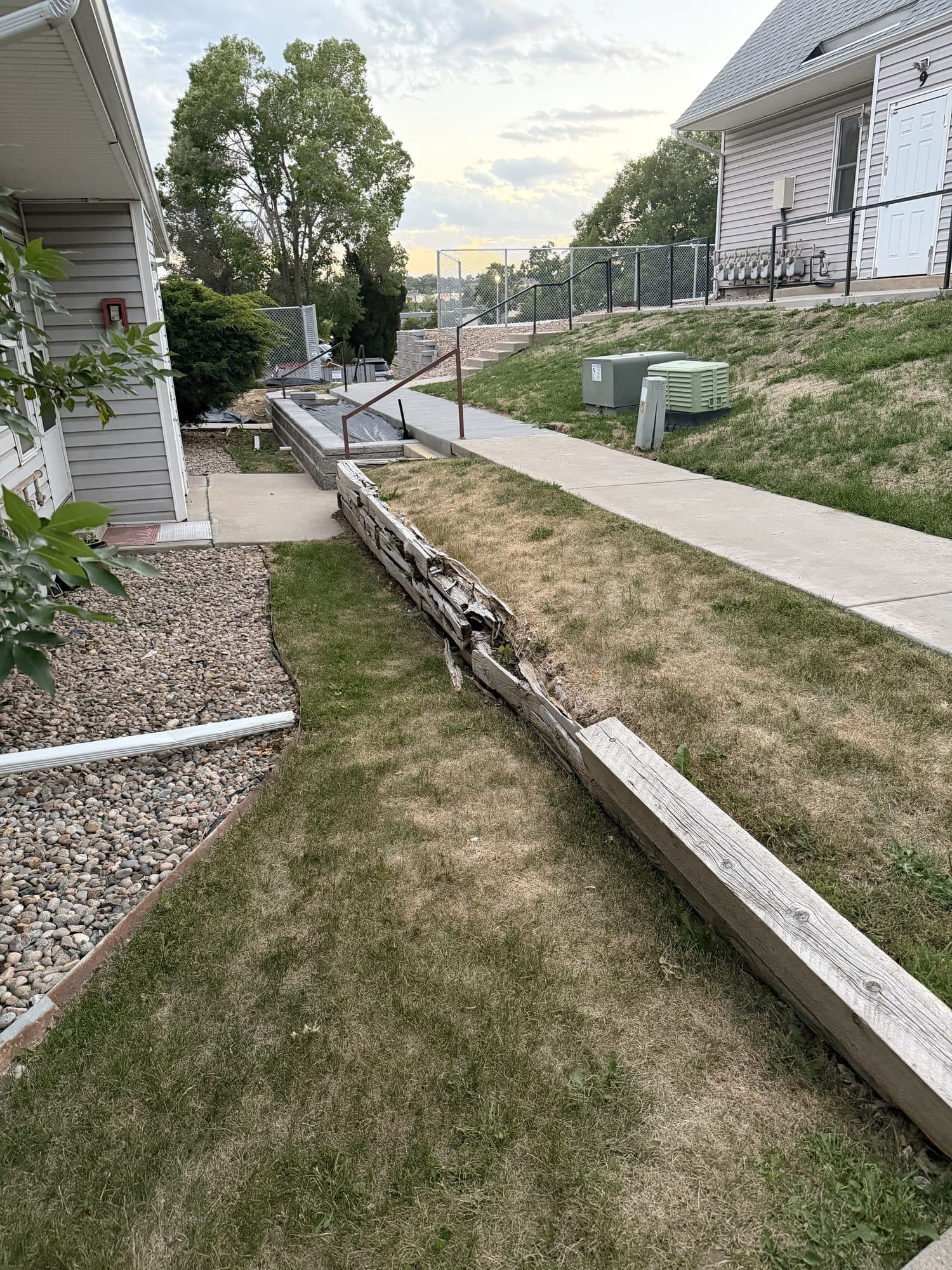 Long leaning timber retaining wall — IMG_1076: Long timber retaining wall leaning outward along a sloped walkway.